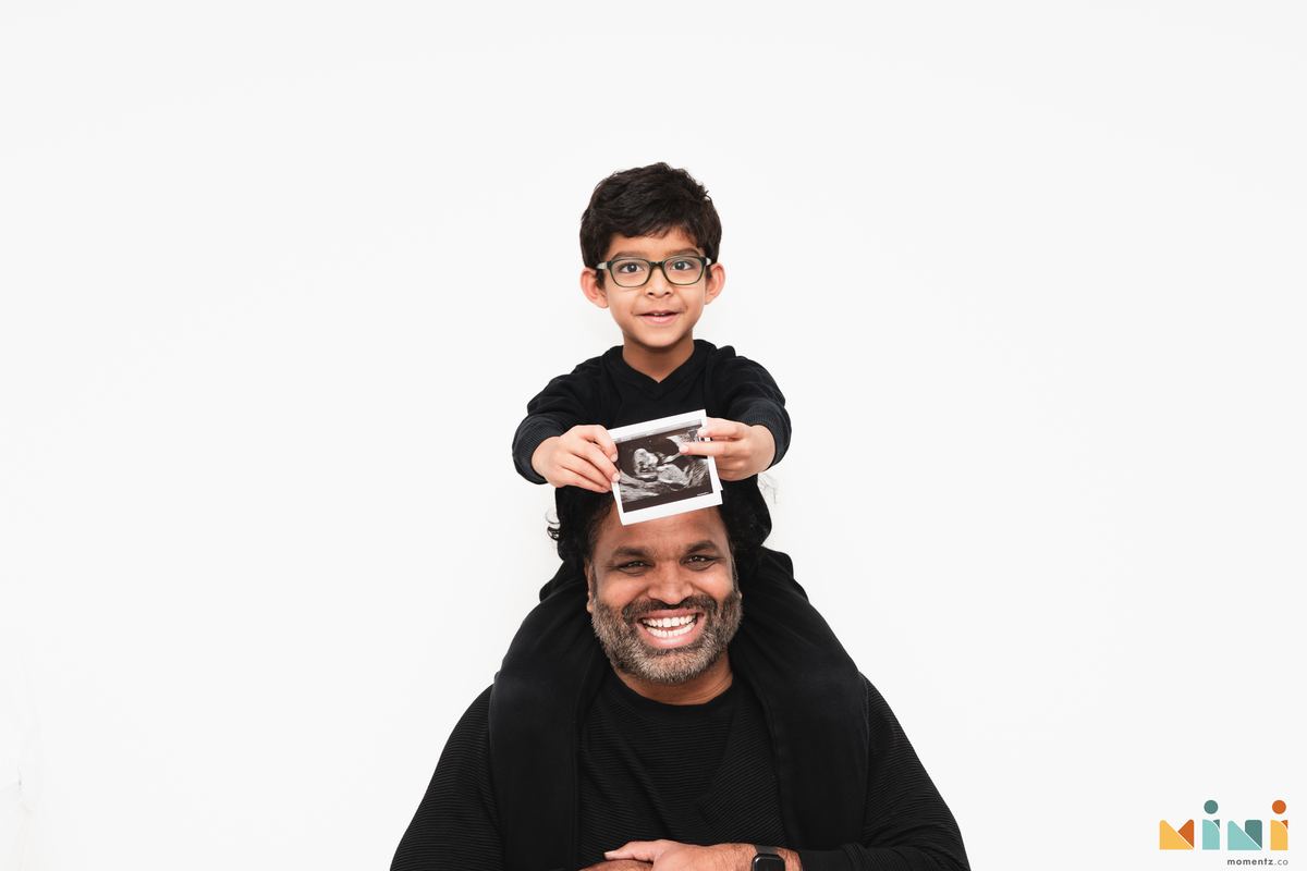Older sibling holding baby scan photo — South Indian maternity photography Mini Momentz UK