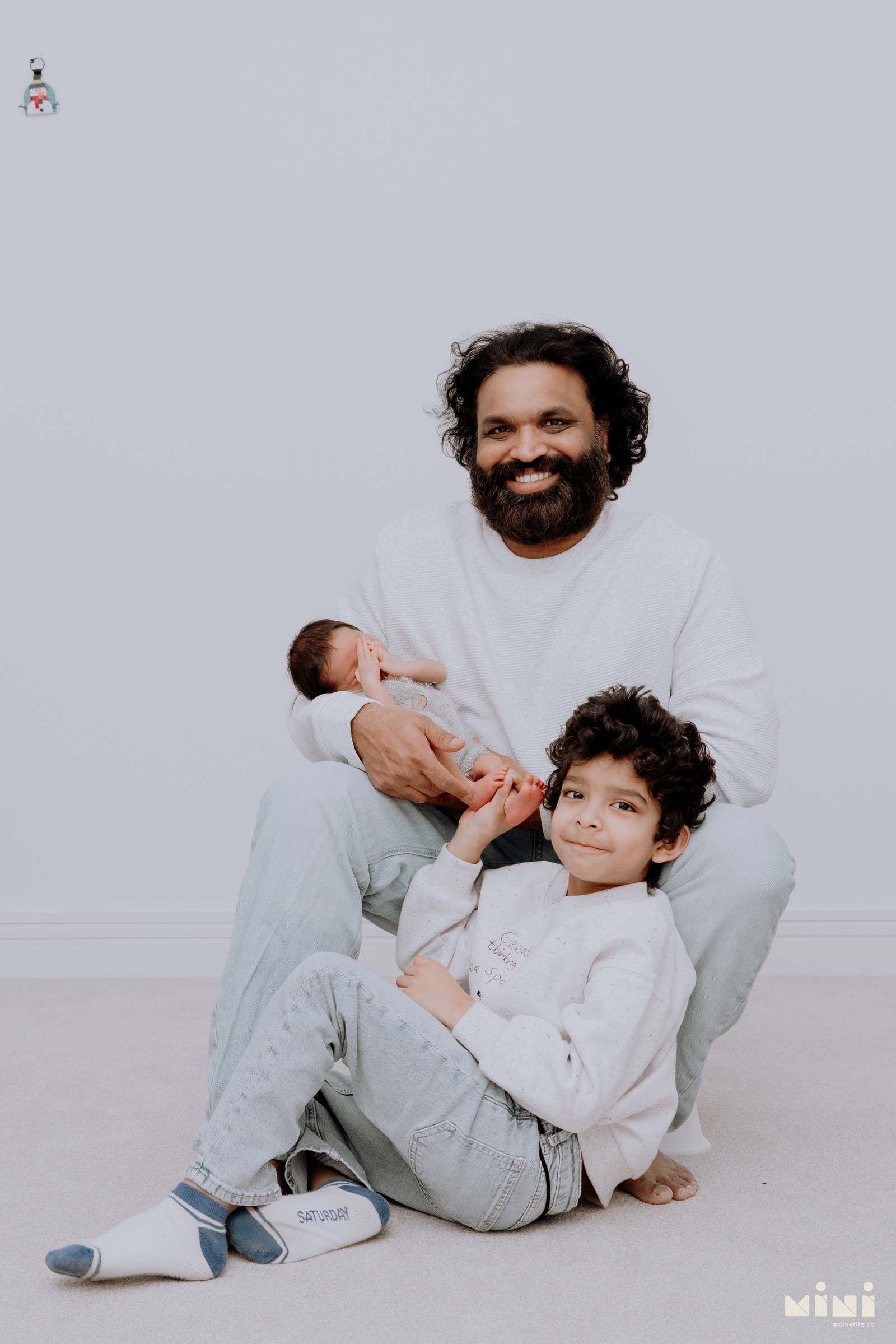 Chaithanya sitting with son Kiwi and his newborn daughter — father with both children during the Mini Momentz Edinburgh newborn photography session