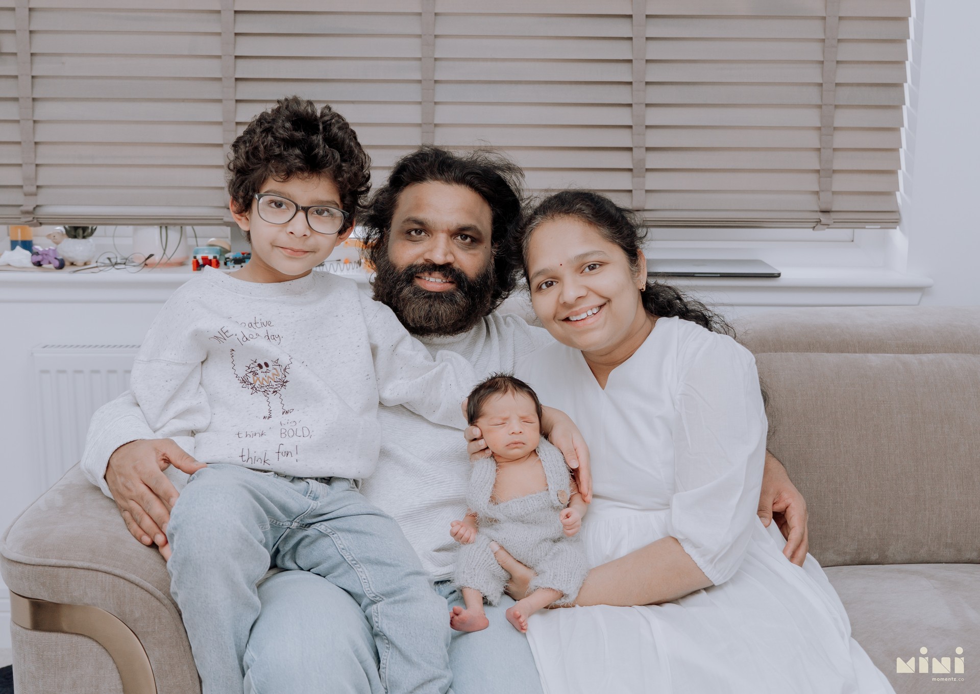 Chaithanya, Sowjanya, Kiwi and their newborn daughter together on the sofa — full family portrait from the Edinburgh home newborn session with Mini Momentz