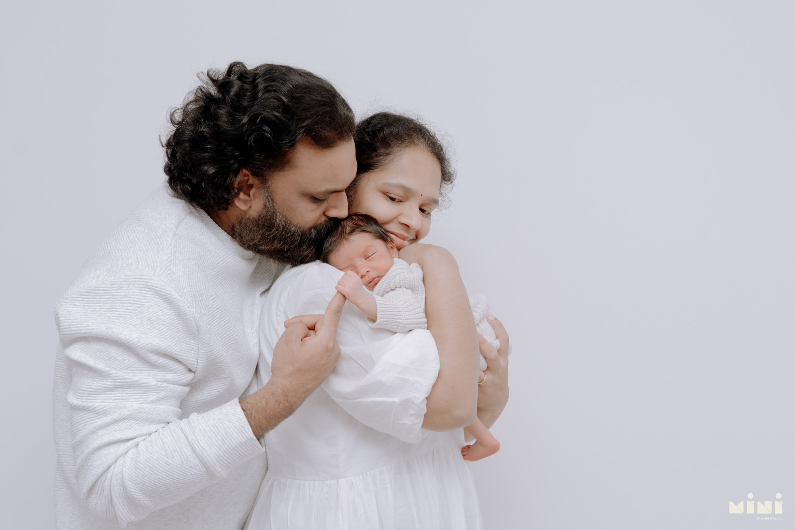 Parents holding newborn baby together during natural light home session