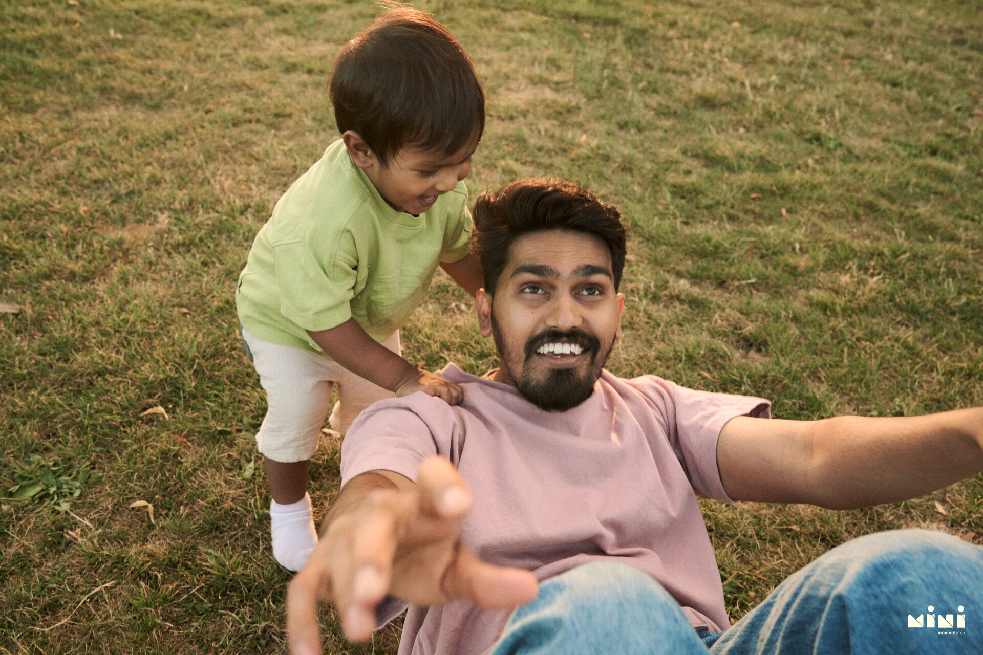 Aaru climbing onto Harsha's shoulders at Victoria Park, Leicester — candid toddler photography by Mini Momentz