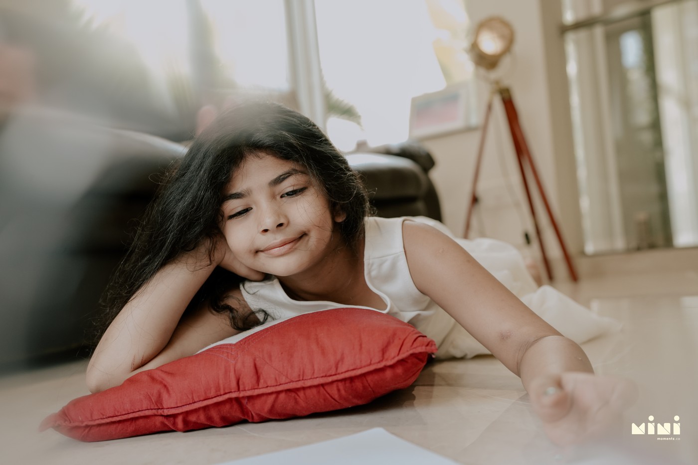 Daughter lying on the floor reading, thoughtful expression — documentary child photography by Mini Momentz South Indian family photographer UK