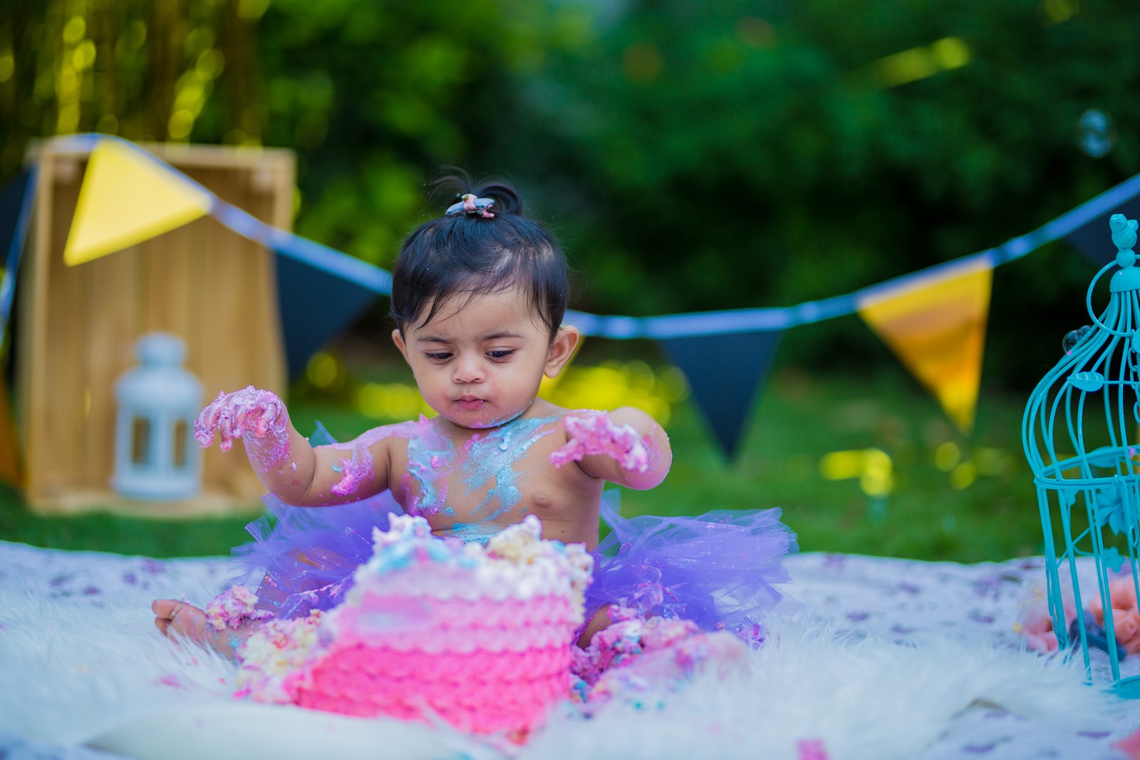Little girl enjoying an outdoor cake smash in the garden