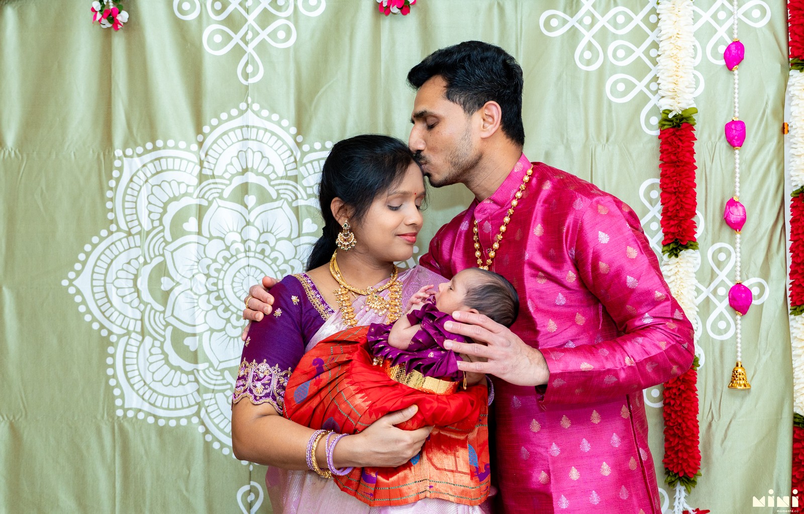 Parents holding newborn during a South Indian naming ceremony
