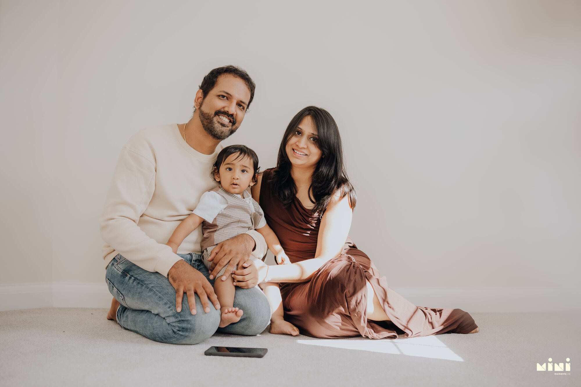 Ramesh, Seema and Sid sitting together indoors in Barkby Thorpe, Leicester — family portrait by Mini Momentz