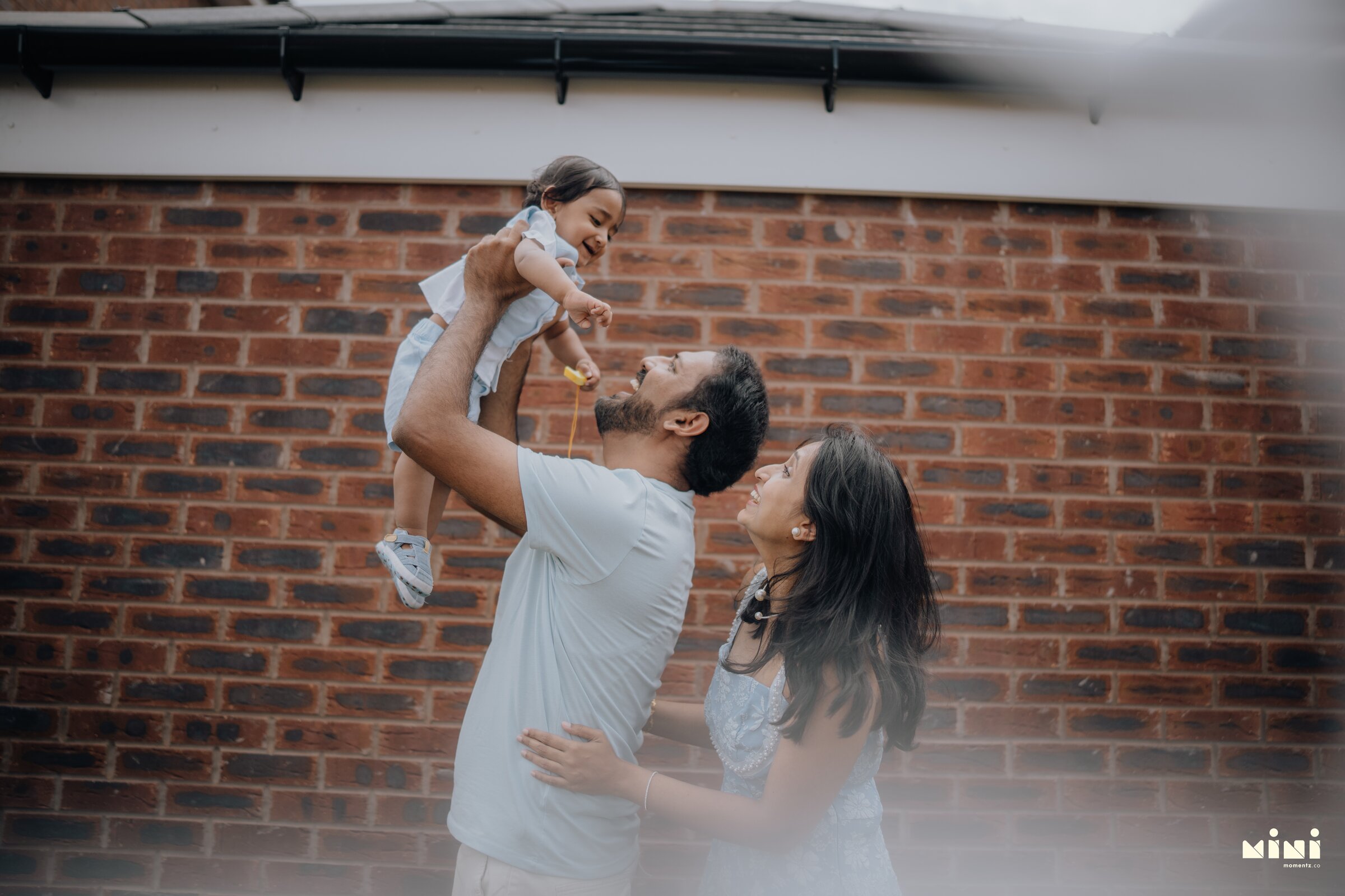 Ramesh lifting Sid while Seema watches during a family storytelling session in Barkby Thorpe, Leicester — Mini Momentz