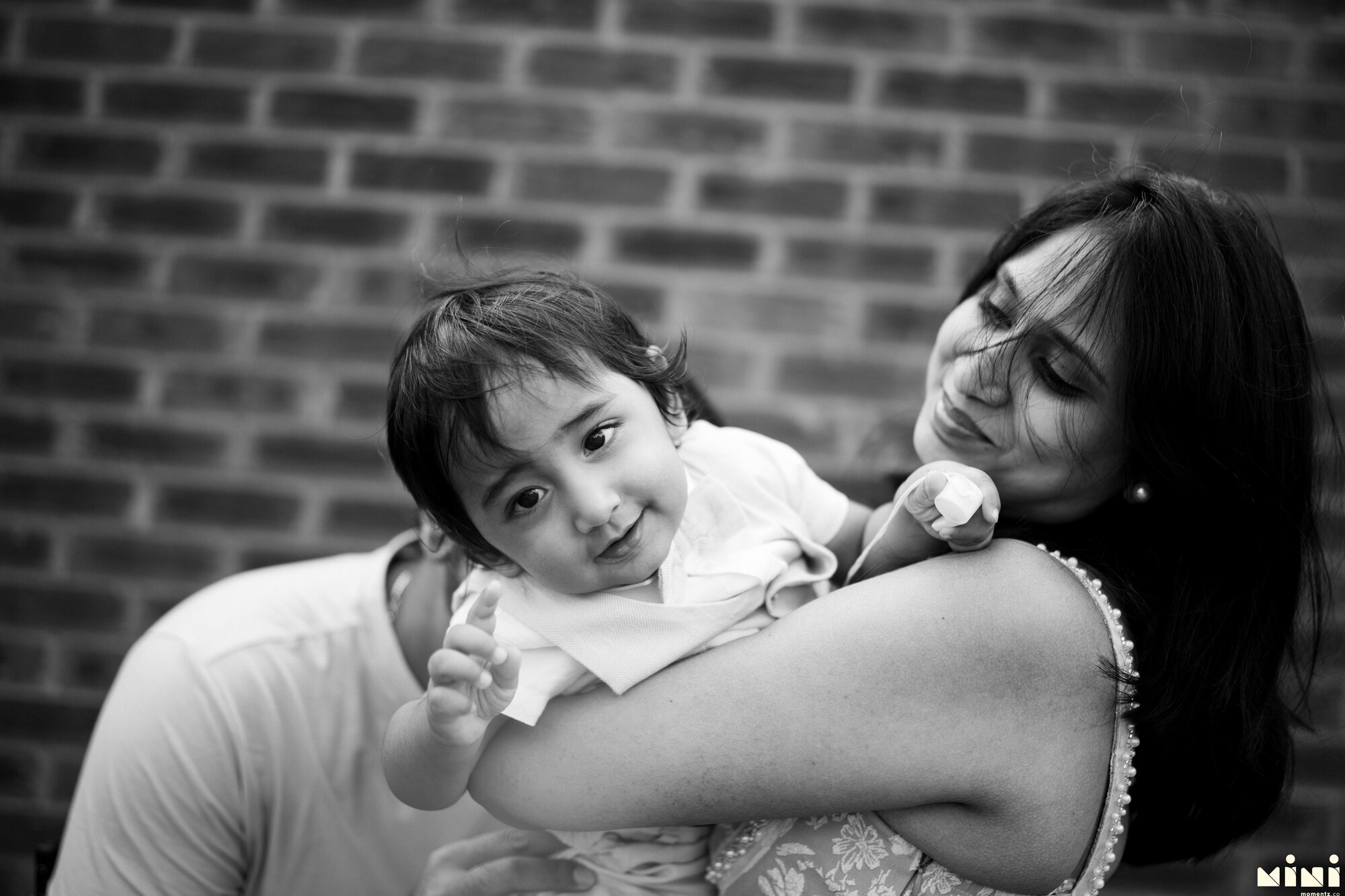 Black and white close portrait of Seema holding Sid outdoors in Barkby Thorpe, Leicester — Mini Momentz