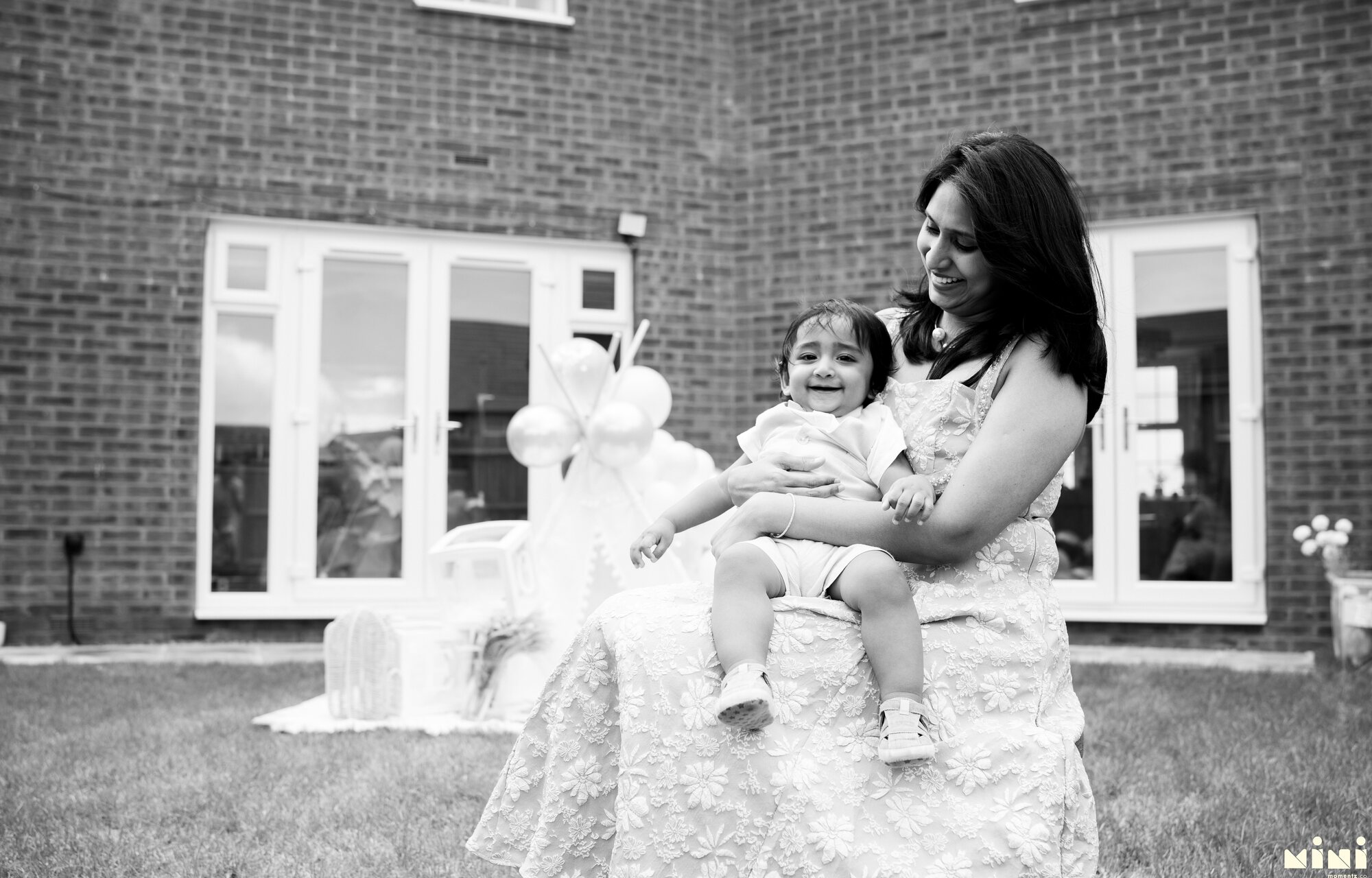 Black and white photograph of Seema sitting with Sid outdoors in Barkby Thorpe, Leicester — Mini Momentz